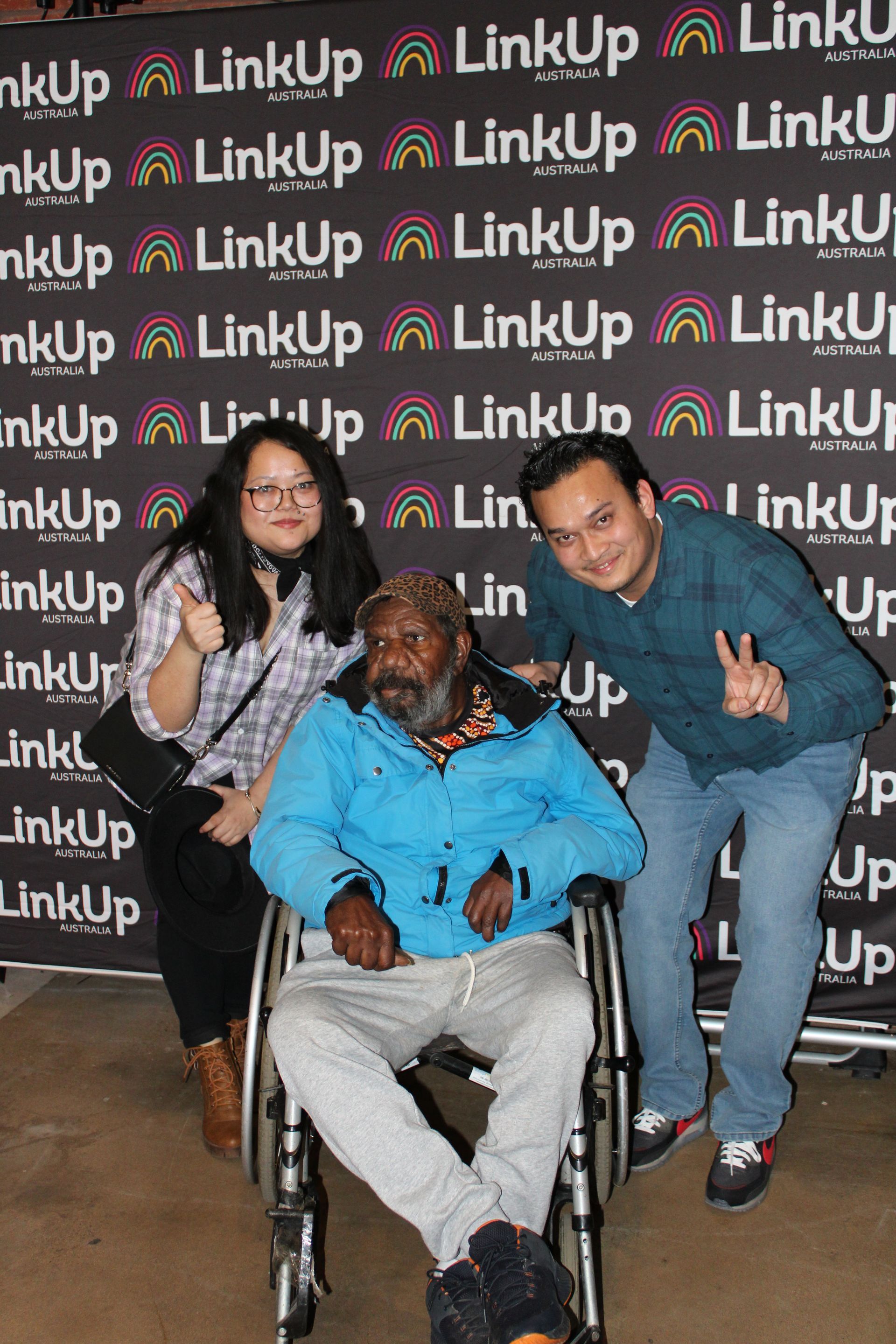 A man in a wheelchair is posing for a picture with two other people.