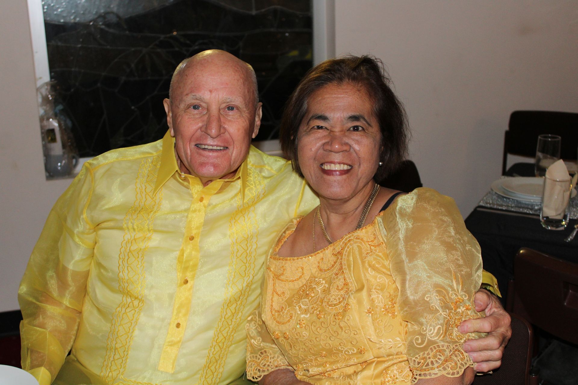 A man and a woman are posing for a picture while sitting at a table.
