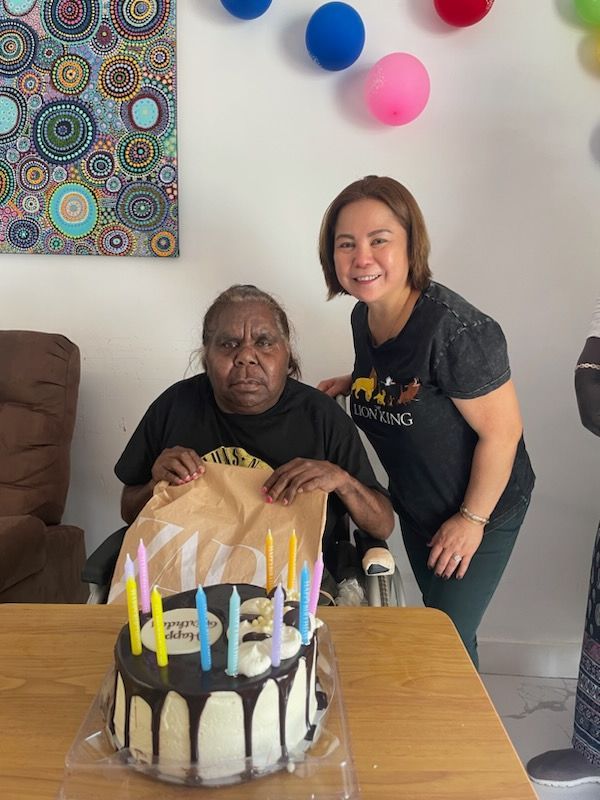 Two women standing next to a cake with candles on it