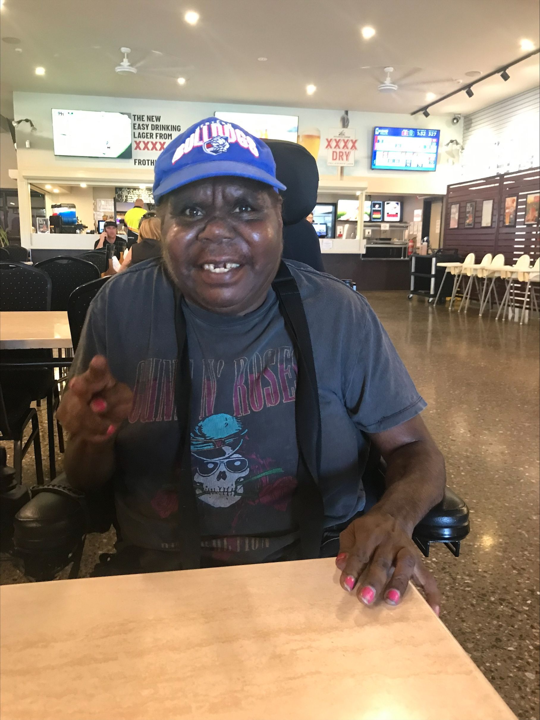 A man in a wheelchair is sitting at a table in a restaurant.