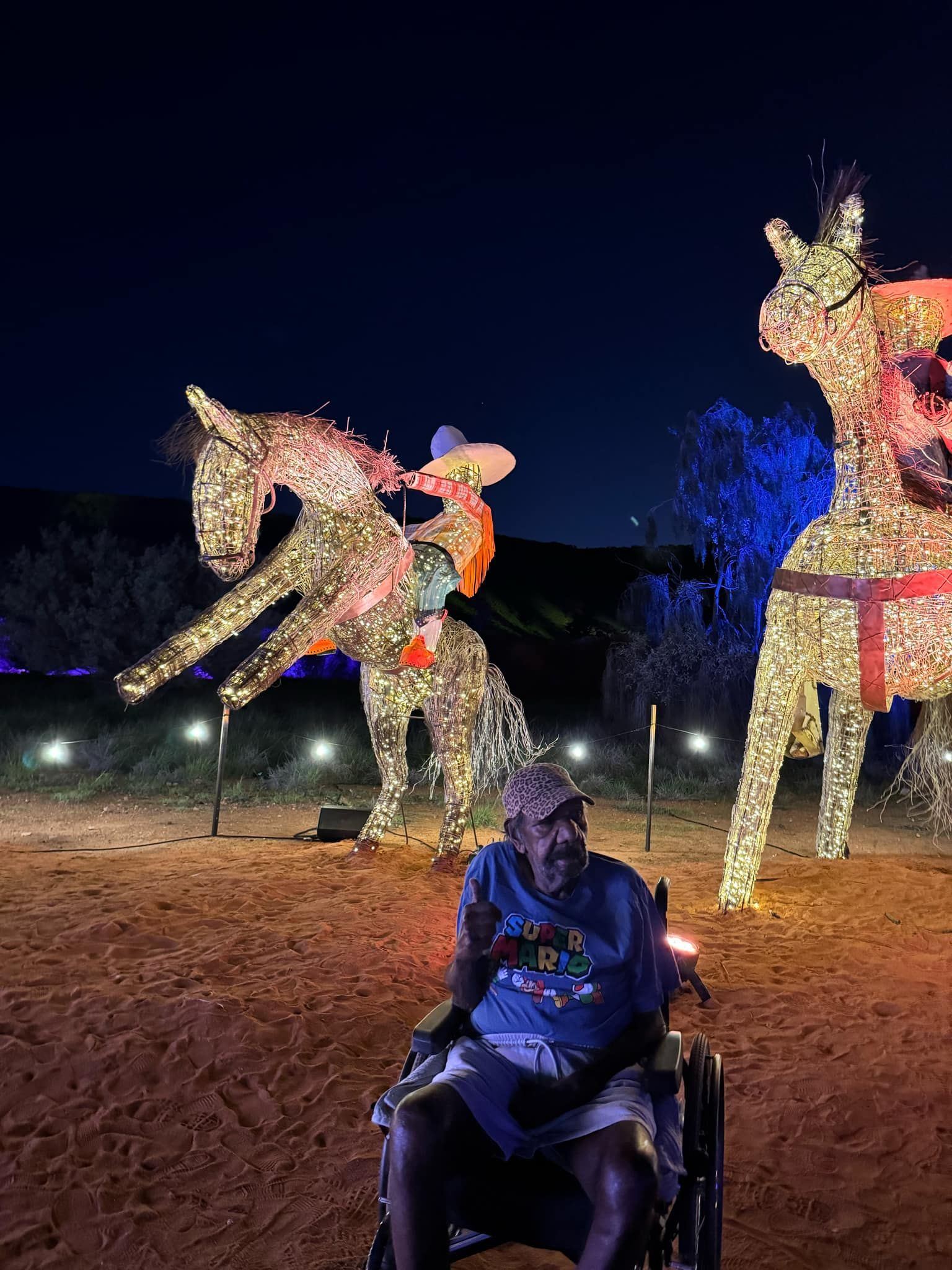 A man in a wheelchair is sitting in front of a statue of a horse.