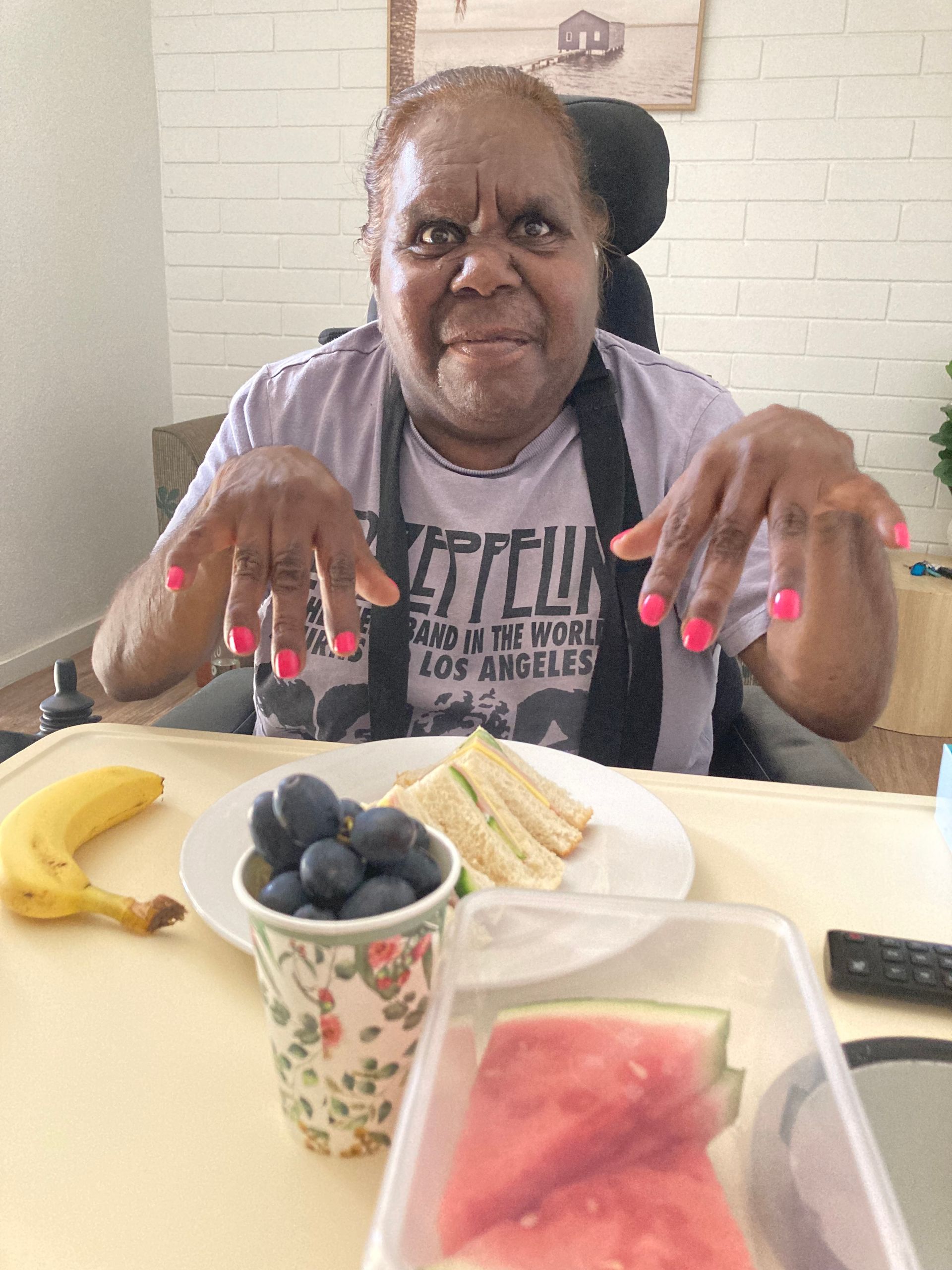 A woman in a wheelchair is sitting at a table with a plate of food.
