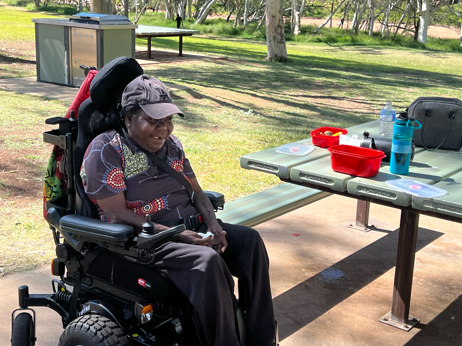 A man in a wheelchair is sitting at a picnic table.