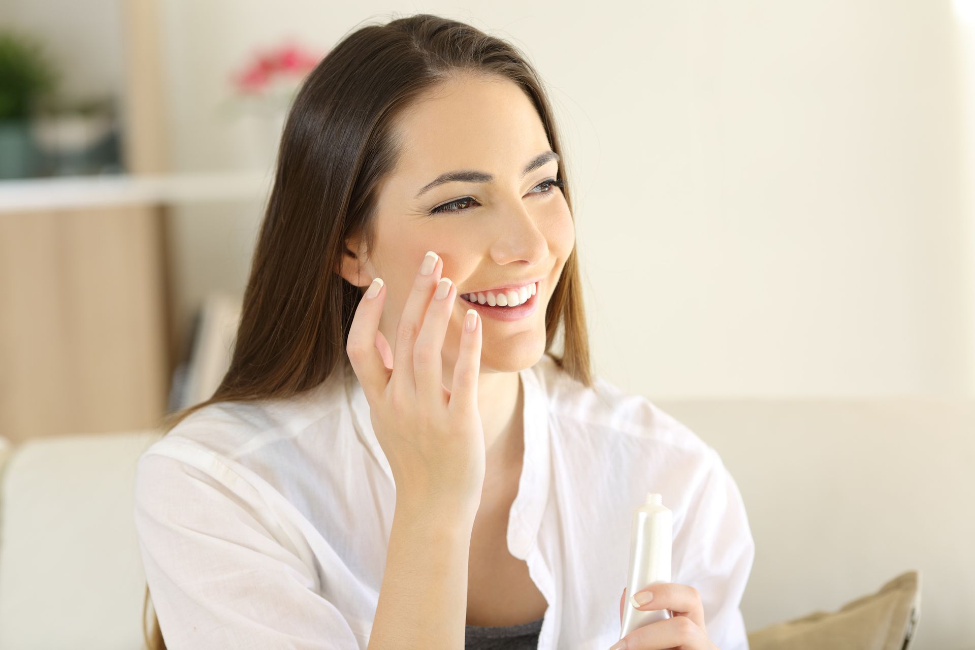 Donna sorridente usa prodotti per il viso