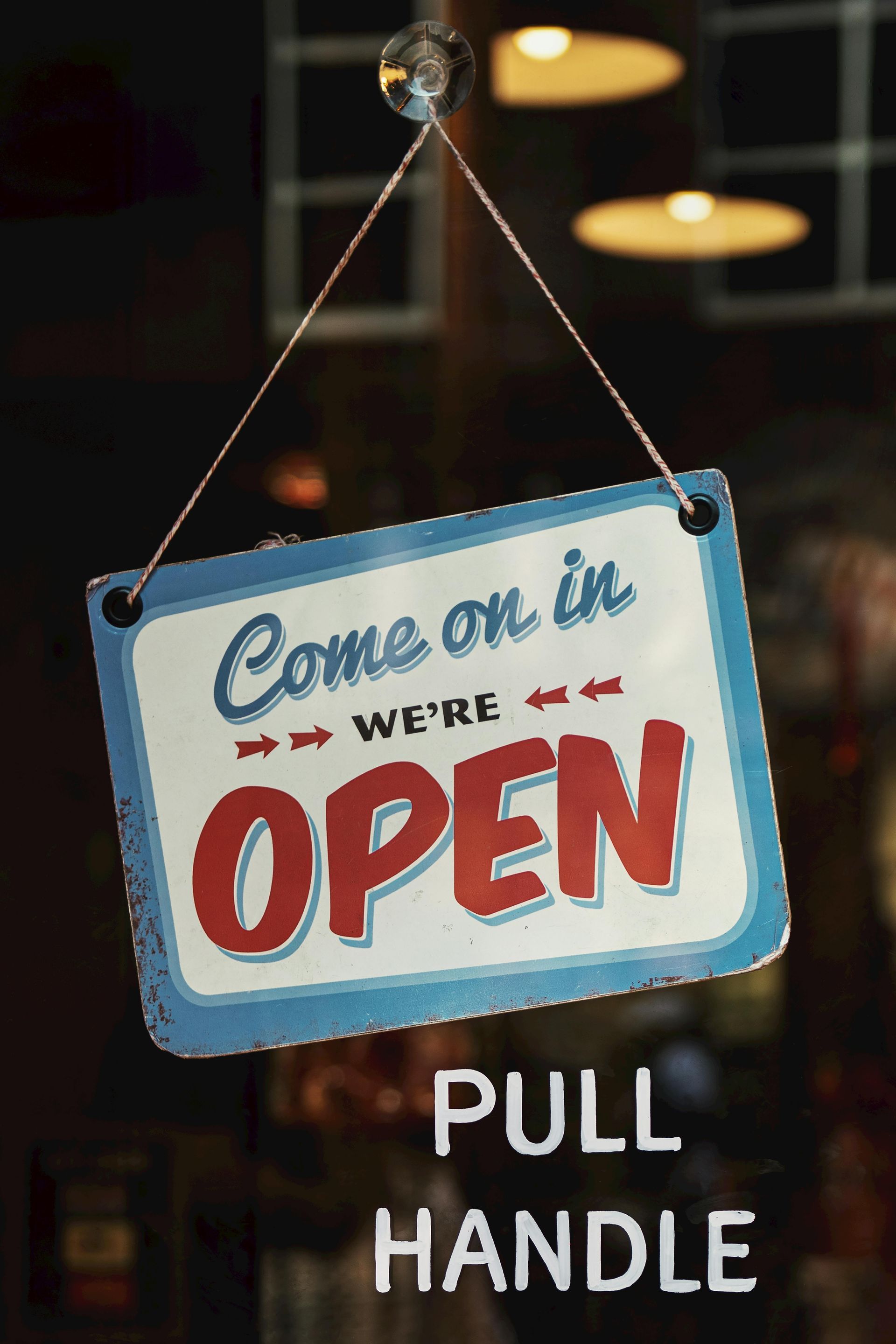 Hanging blue and white “Come on in, we’re OPEN” sign with “PULL HANDLE” text below.