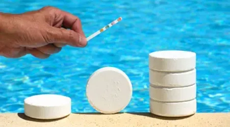 A person is holding a test strip next to a stack of chlorine tablets.