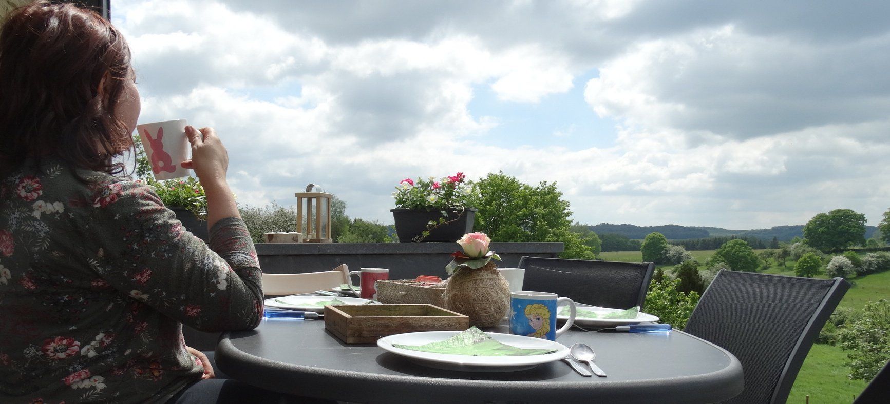 Une femme est assise à une table avec une tasse sur laquelle figure un chien