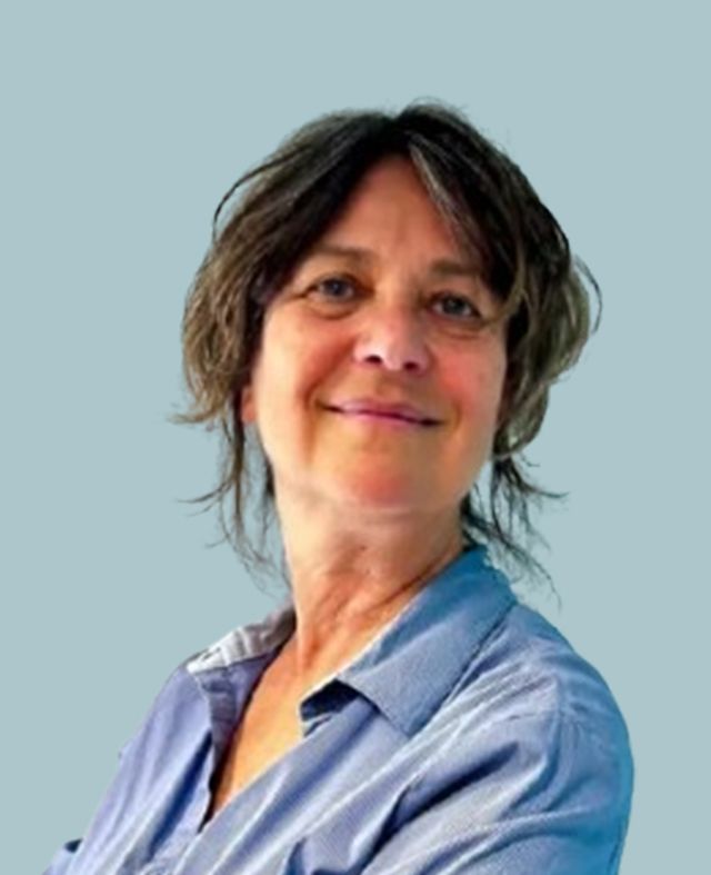 Una donna con una camicia blu è in piedi con le braccia incrociate