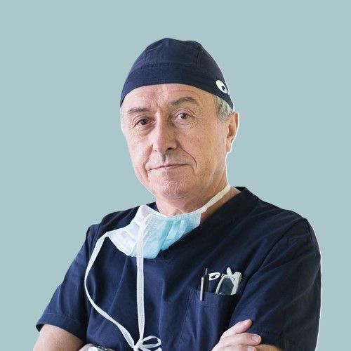 Un uomo che indossa una cuffia chirurgica e una maschera è in piedi con le braccia incrociate