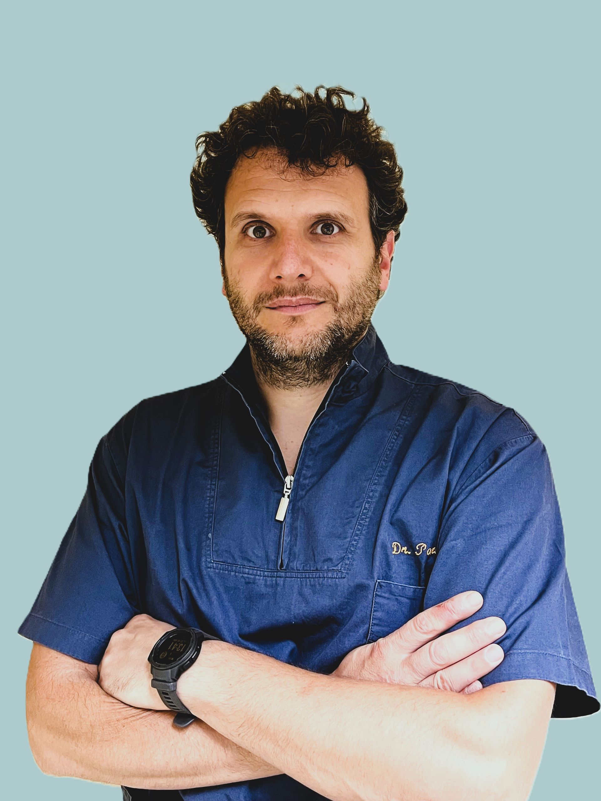 Un uomo con i capelli ricci e la barba indossa una camicia blu