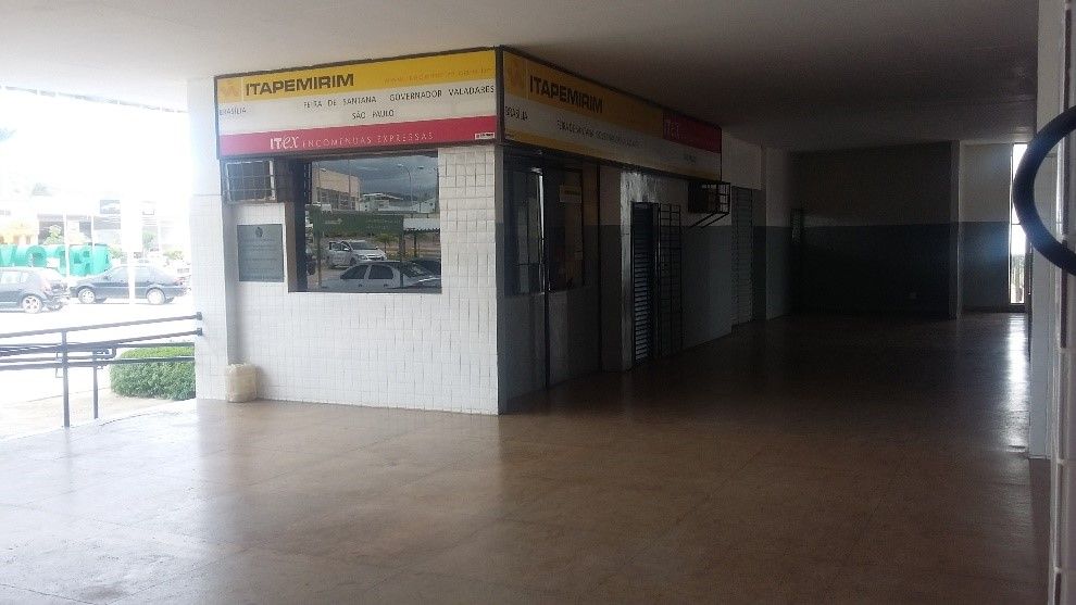 Homem na sala de controle falando ao telefone, supervisionando ônibus estacionados ao ar livre sob abrigo.