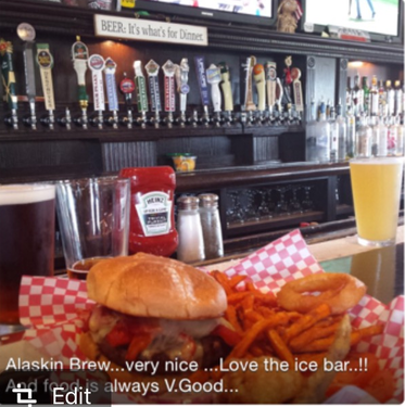 Burger and fries on a bar with many beer taps and a drink.