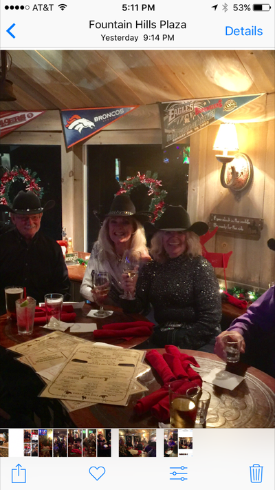 People in cowboy hats at a restaurant, seated at a table, drinks and menus visible. Broncos banners in the background.