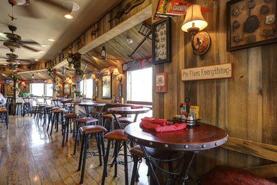 Rustic-themed restaurant interior with wood paneling, tables, bar stools, and decorations.