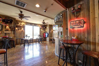Interior of Four Peaks Brewing Co. Bar, with wood paneling, tables, barstools, and a neon sign.