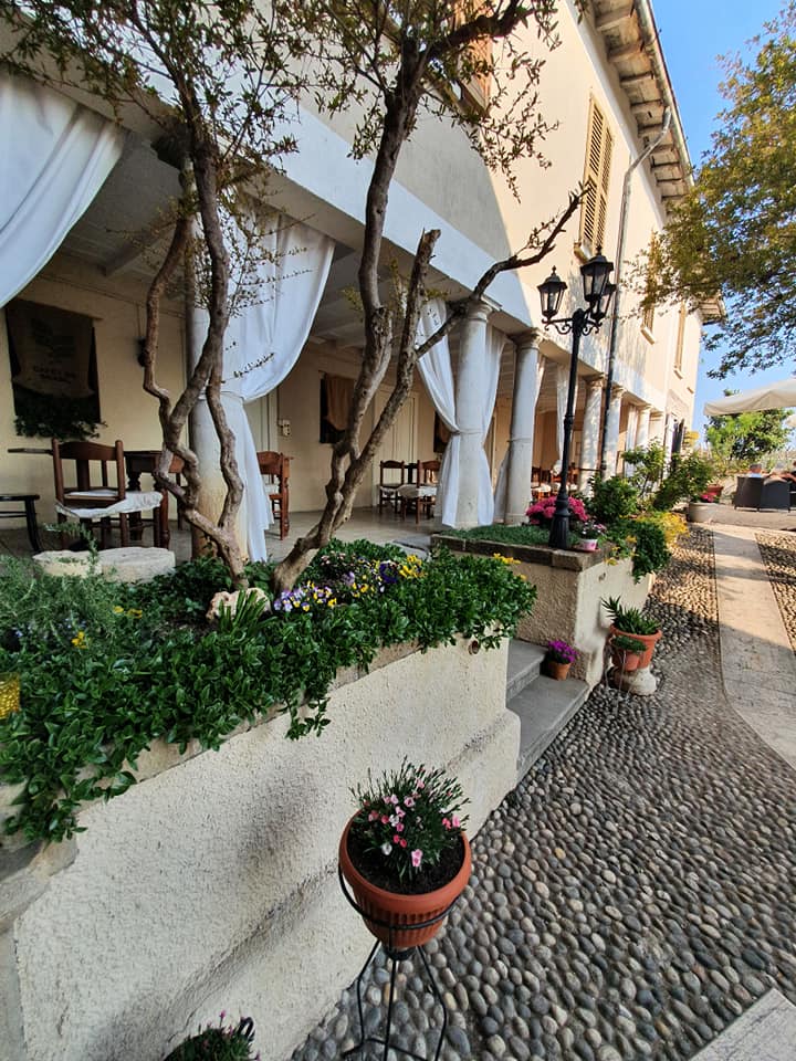 dehors di una trattoria con tende bianche e aiuole