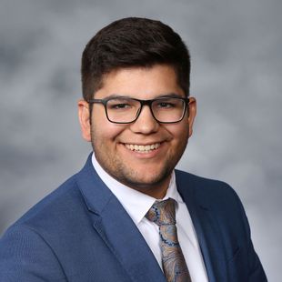 A young man in a suit and tie is smiling for the camera.