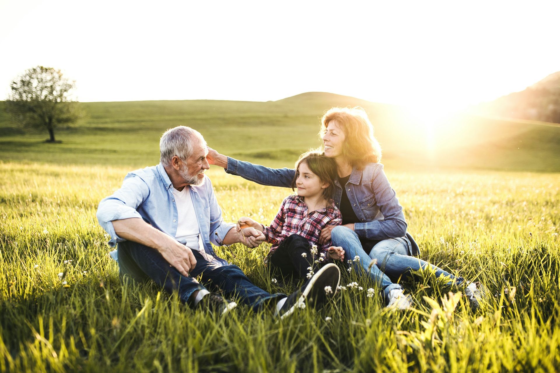 A family is sitting in the grass in a field.