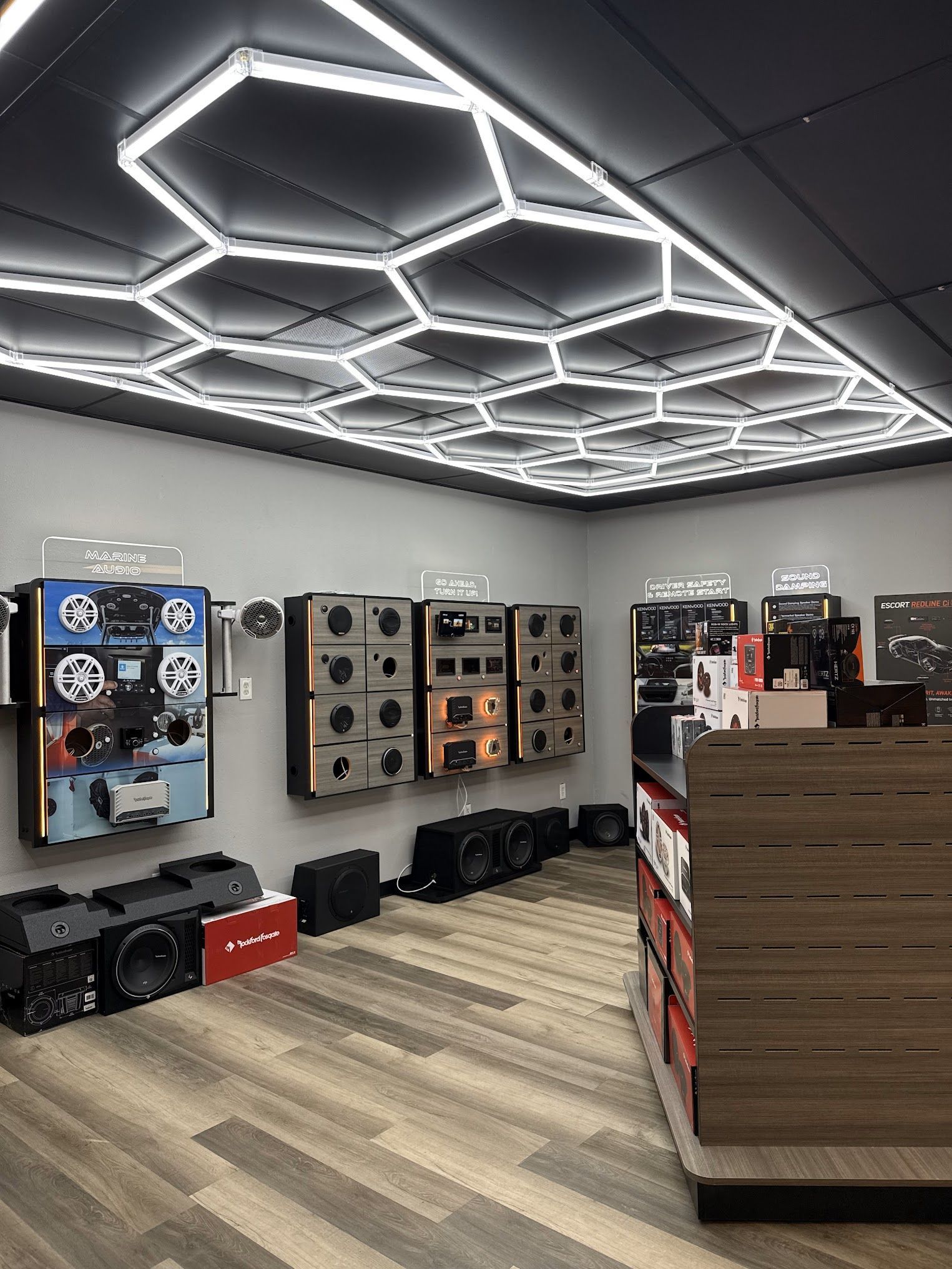 Black and brown customized golf cart with large tires, speakers, and cushioned seats in a showroom.