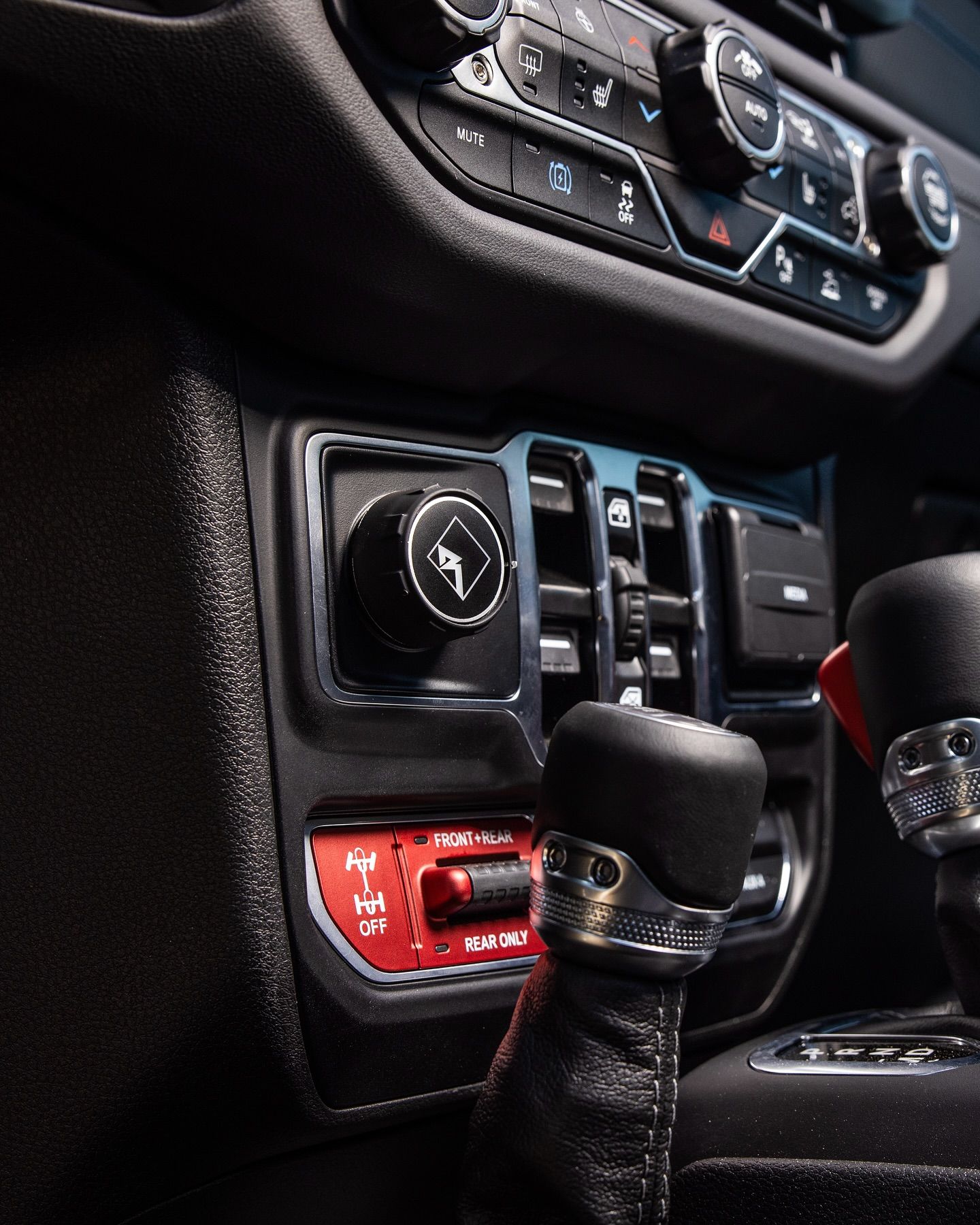 Interior view of a car console with a gear shift, controls, and dials in black and silver.