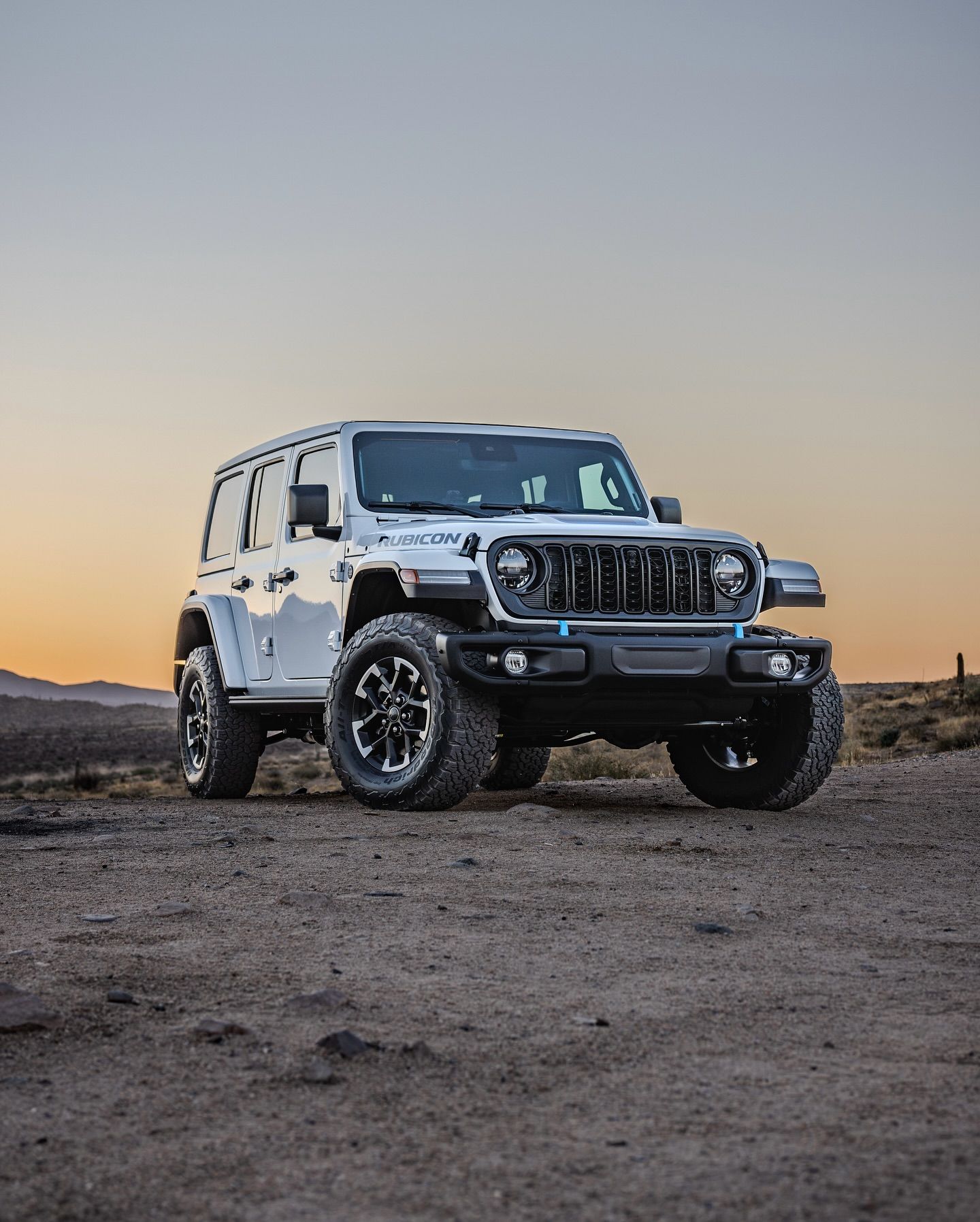 White Jeep Wrangler parked on dirt road at dusk.