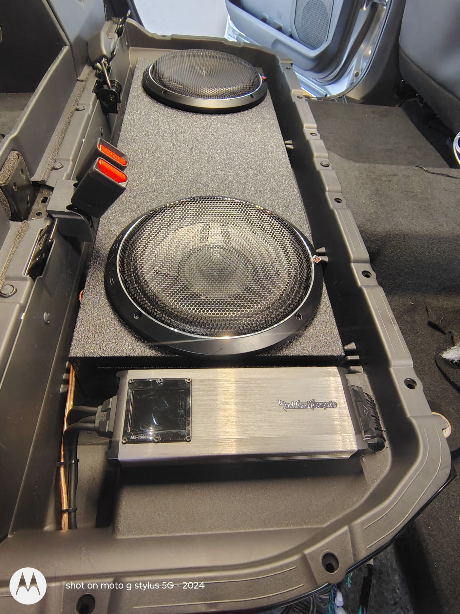 Car audio system with two subwoofers, a subwoofer enclosure, and an amplifier installed in a vehicle.