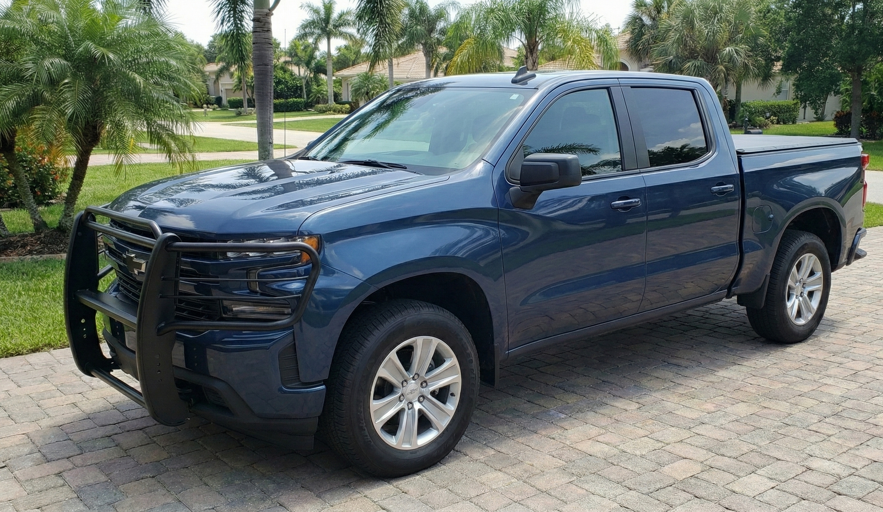 A white tow truck towing a white semi-truck cab on a road, both moving.