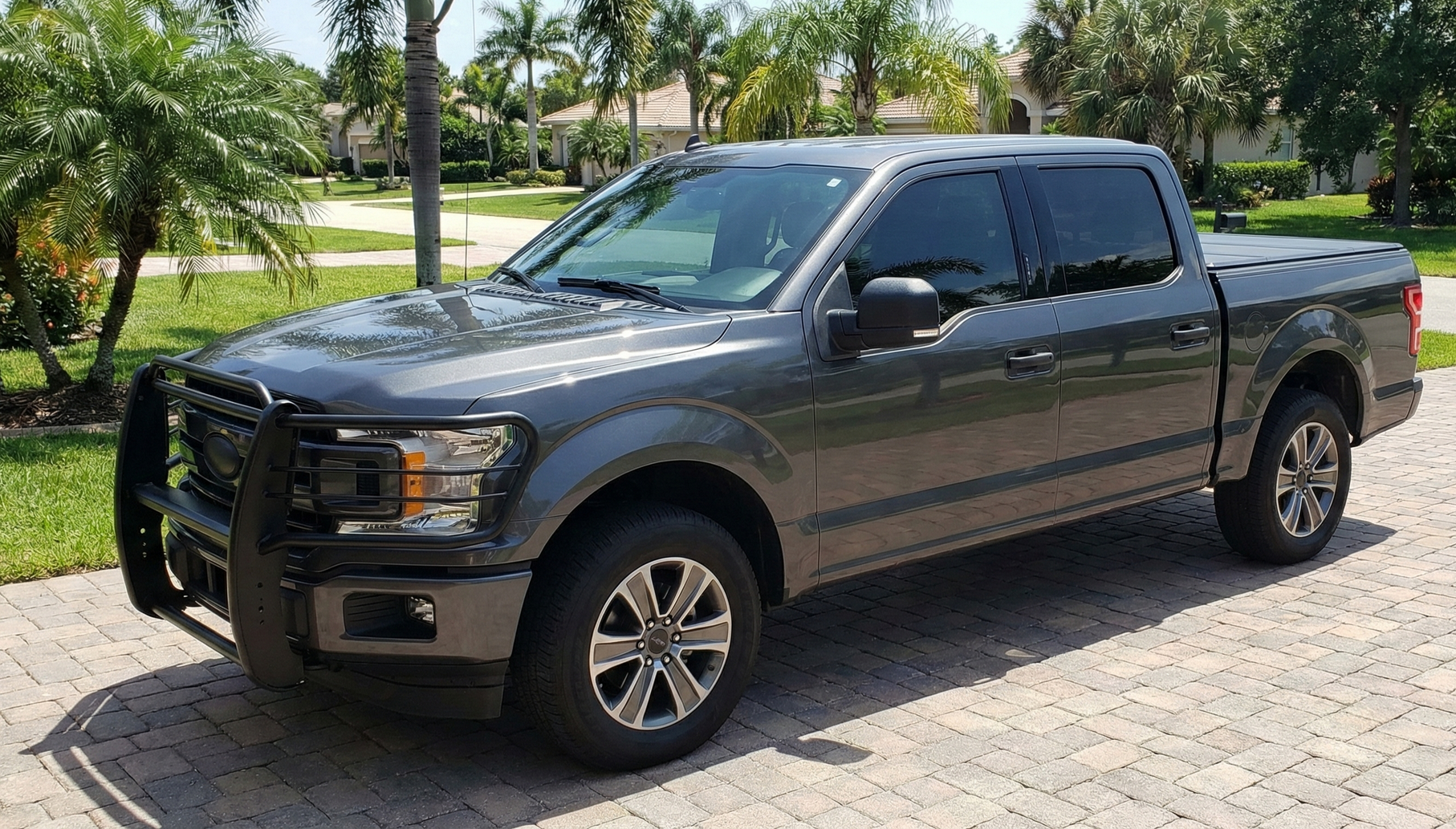 Blue semi-truck parked in a paved lot. Front view with a mountain in the background.