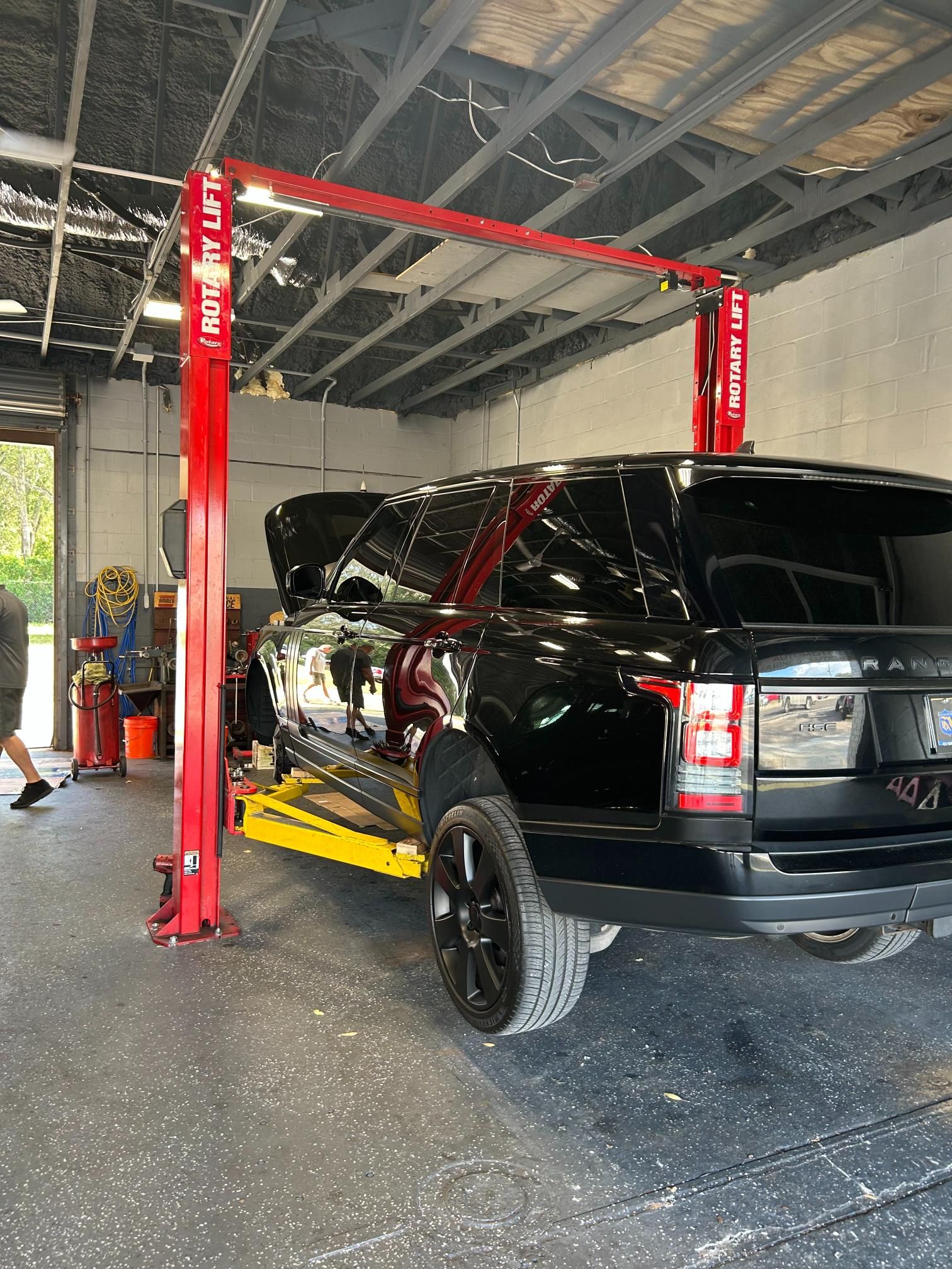 Black Range Rover on a car lift in a garage with red lift arms.