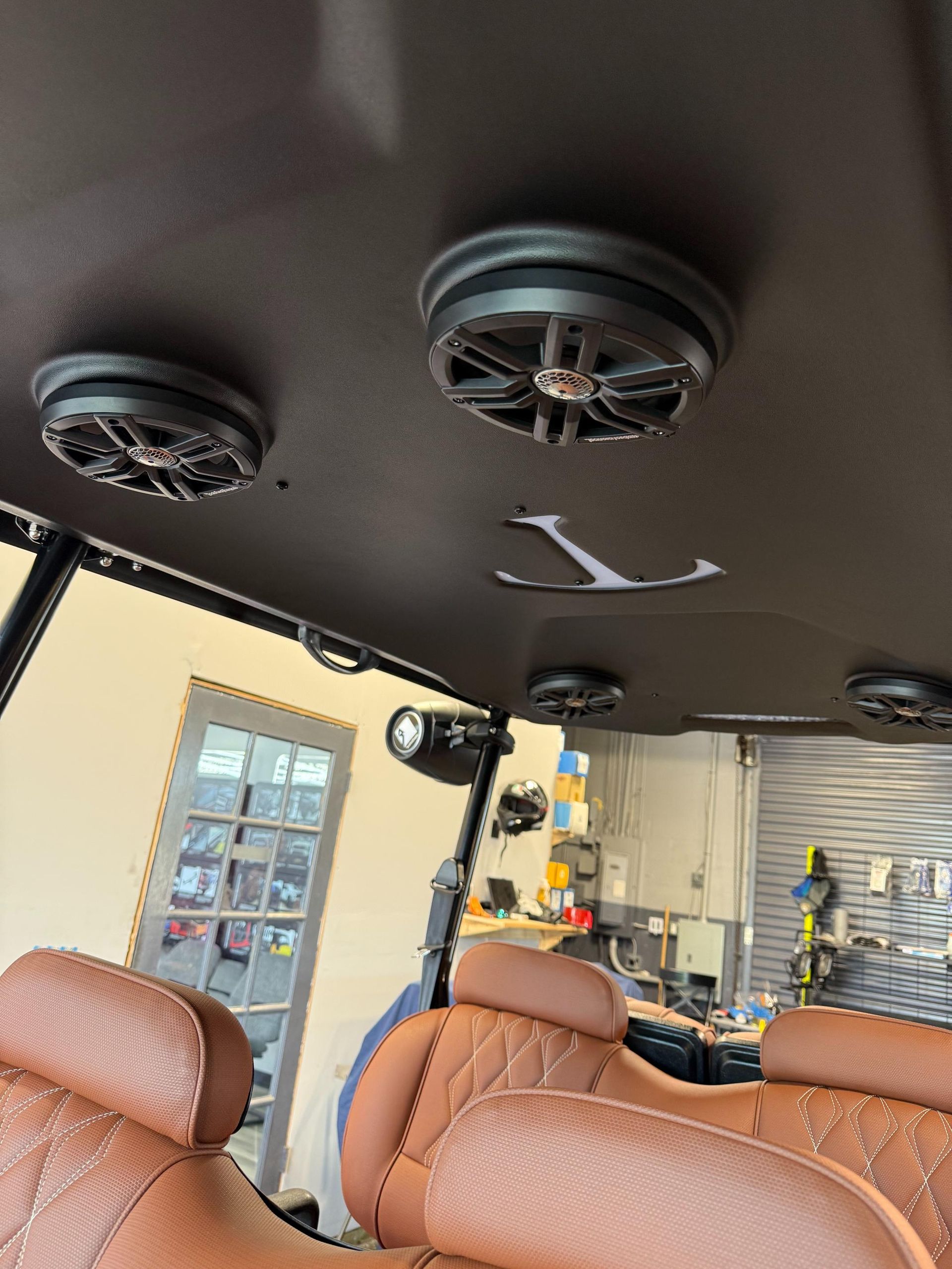 Brown golf cart interior with speakers, custom seats, and a black roof.