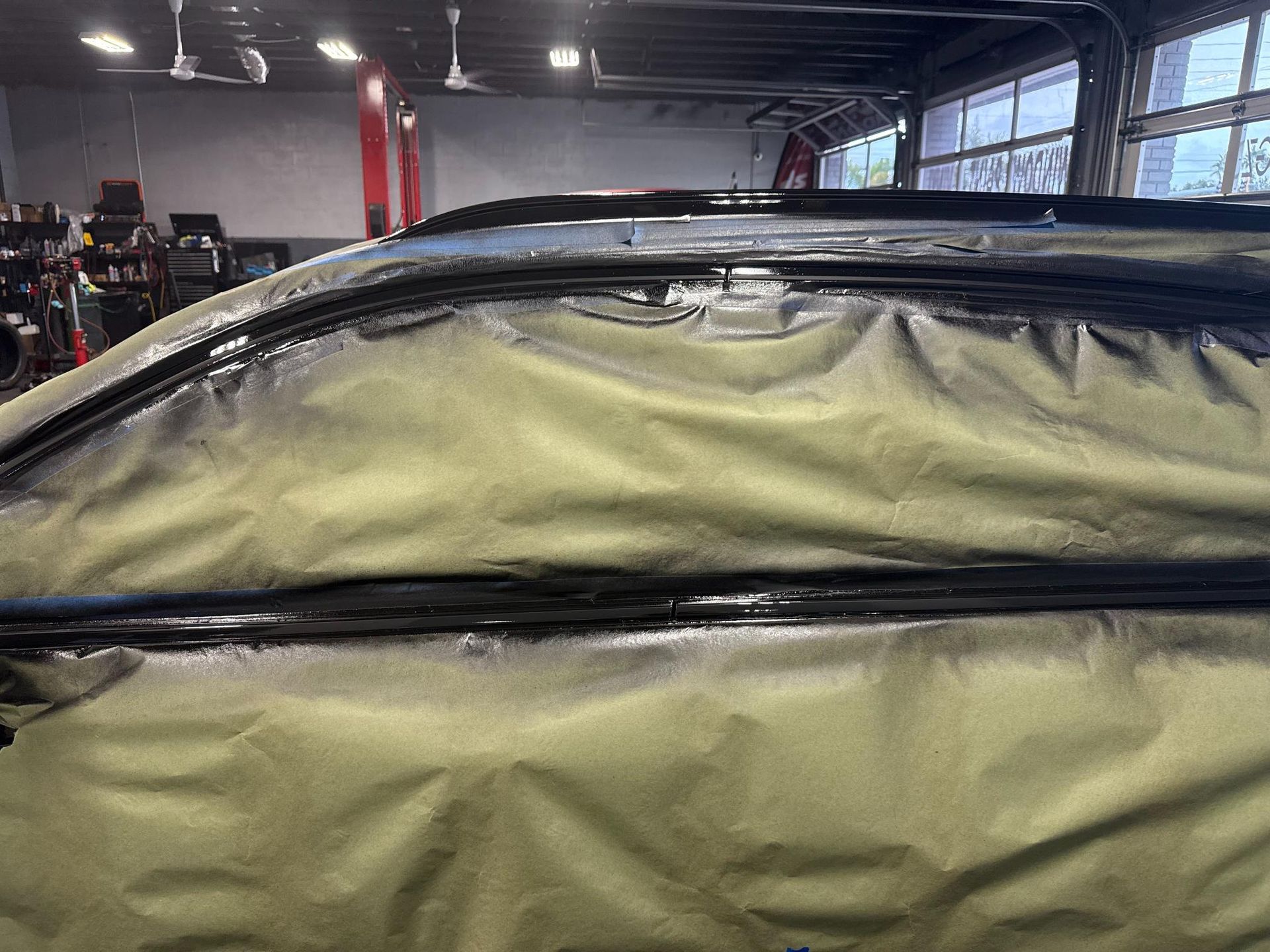 Car roof masked with paper, ready for painting in a garage.