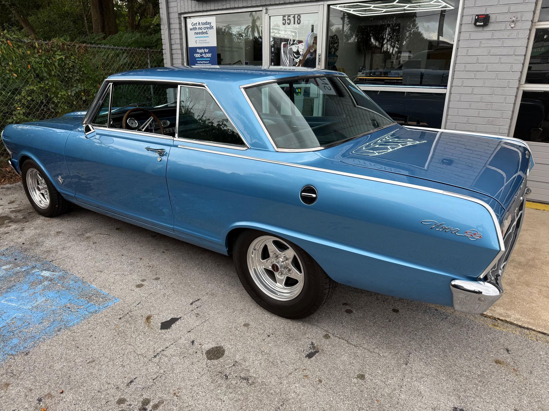 Blue classic Chevrolet Nova parked outside a building.