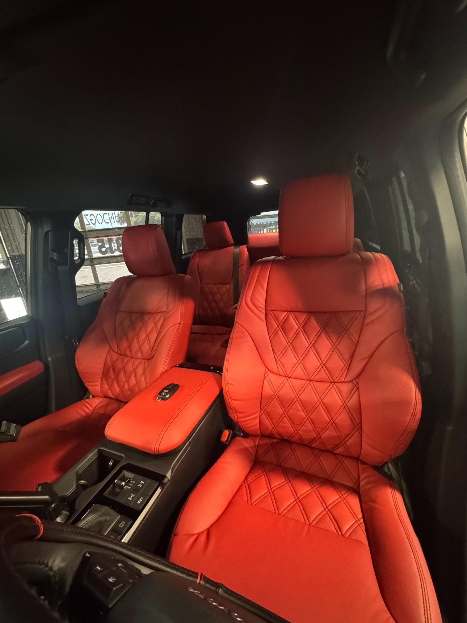 Red leather car interior with diamond-stitched seats and dark accents.