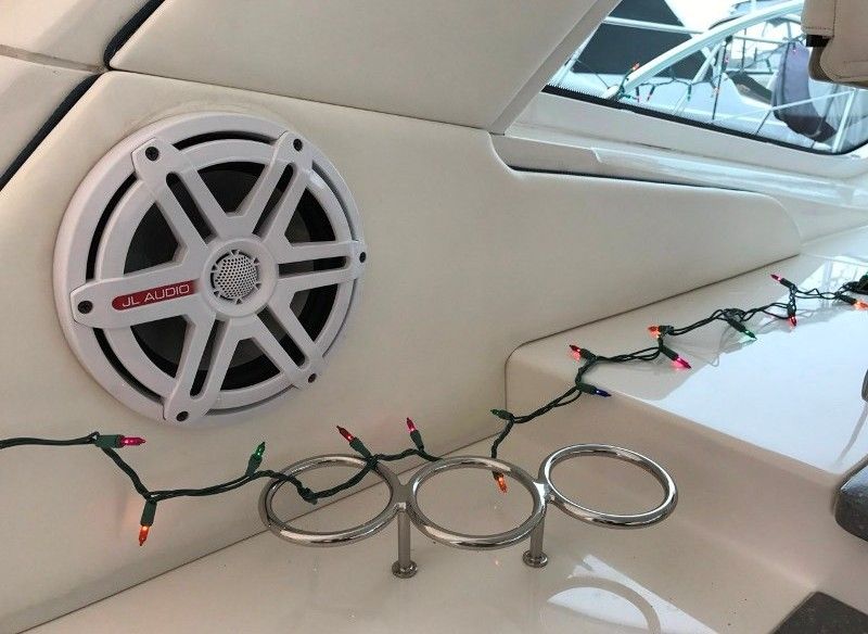 White marine speaker and cup holders decorated with Christmas lights on a boat.