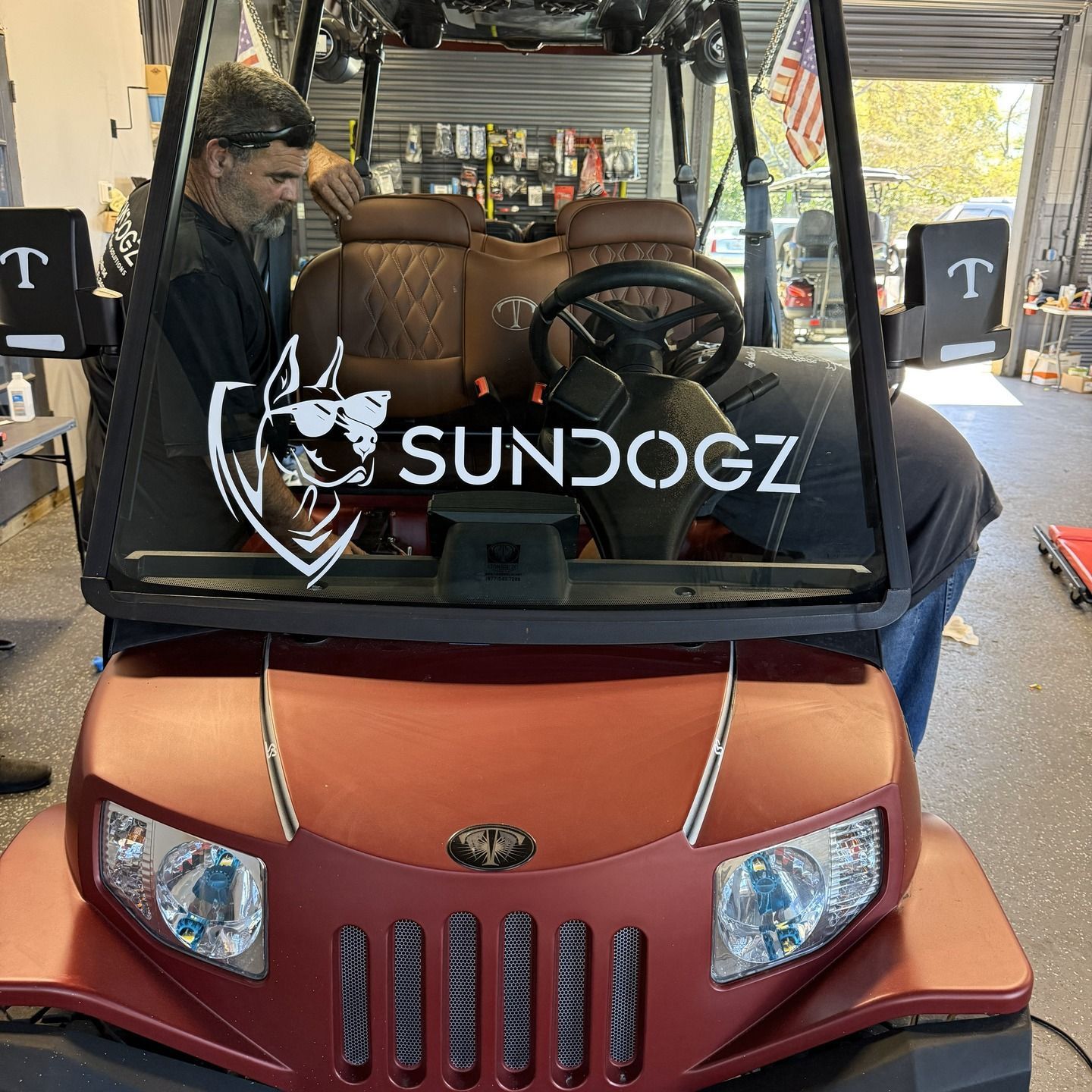 Two men working on a red golf cart with a 