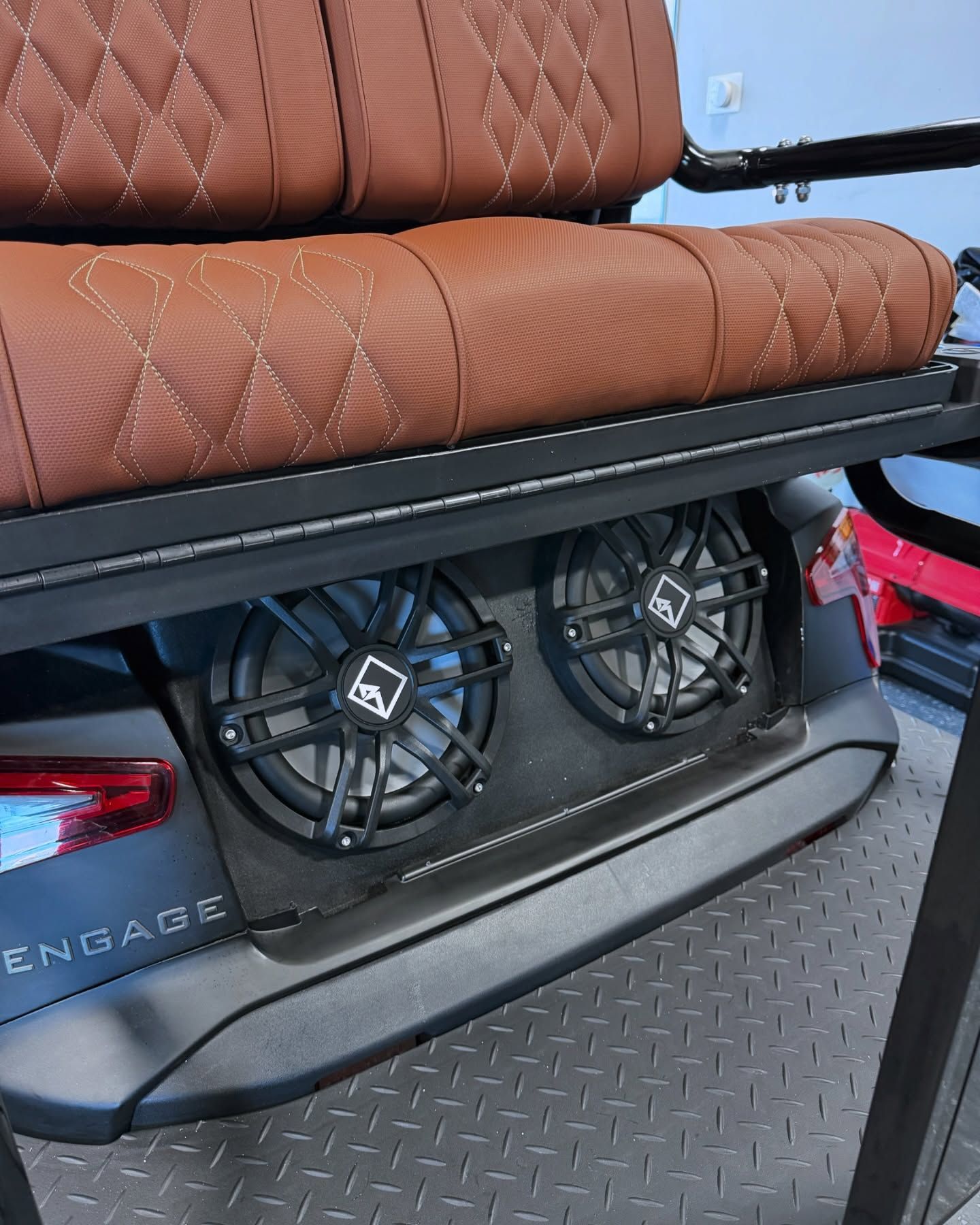 Brown leather golf cart seat above two black speakers.
