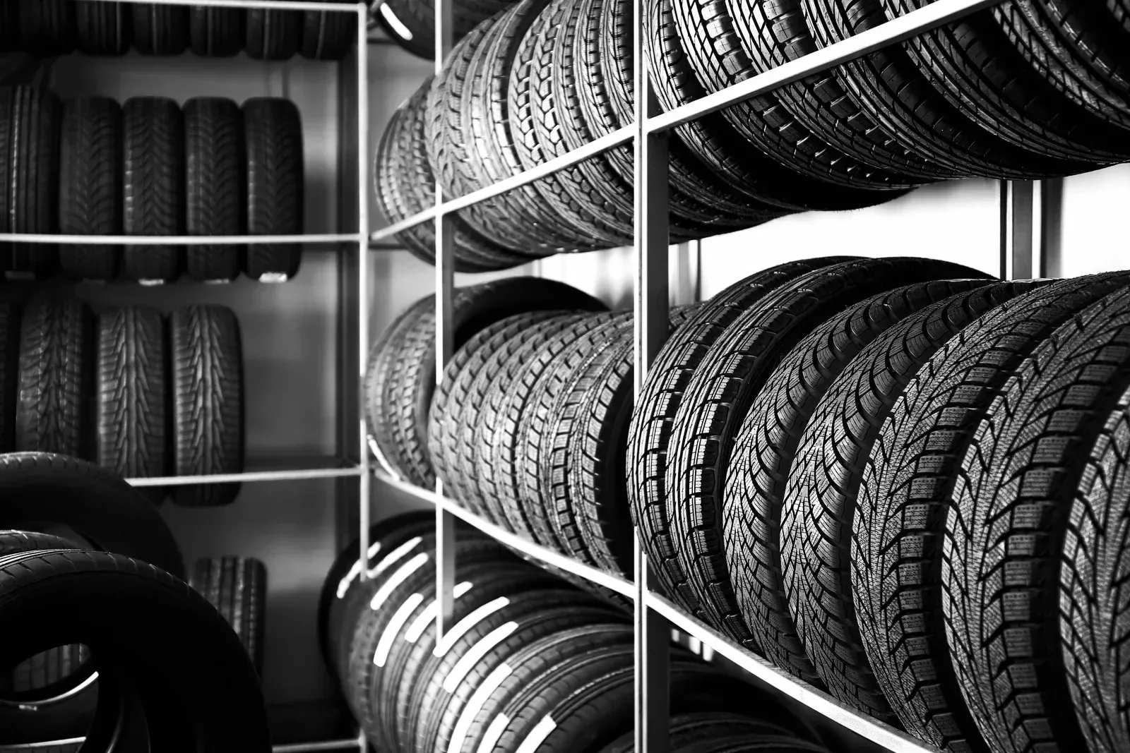 Black and white image of tires stacked on shelves in a tire shop.