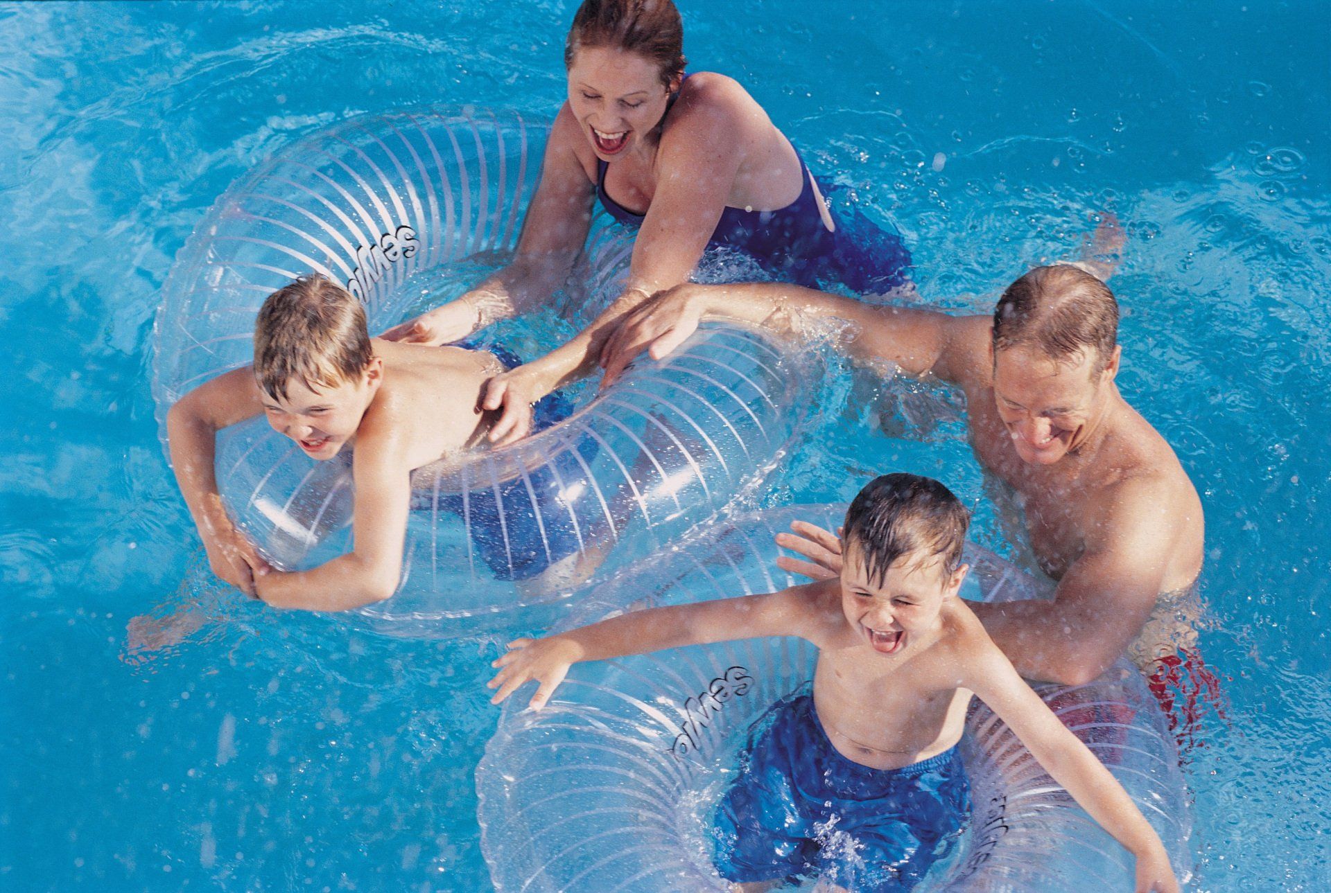 Family In Swimming Pool with Inflatable Rings