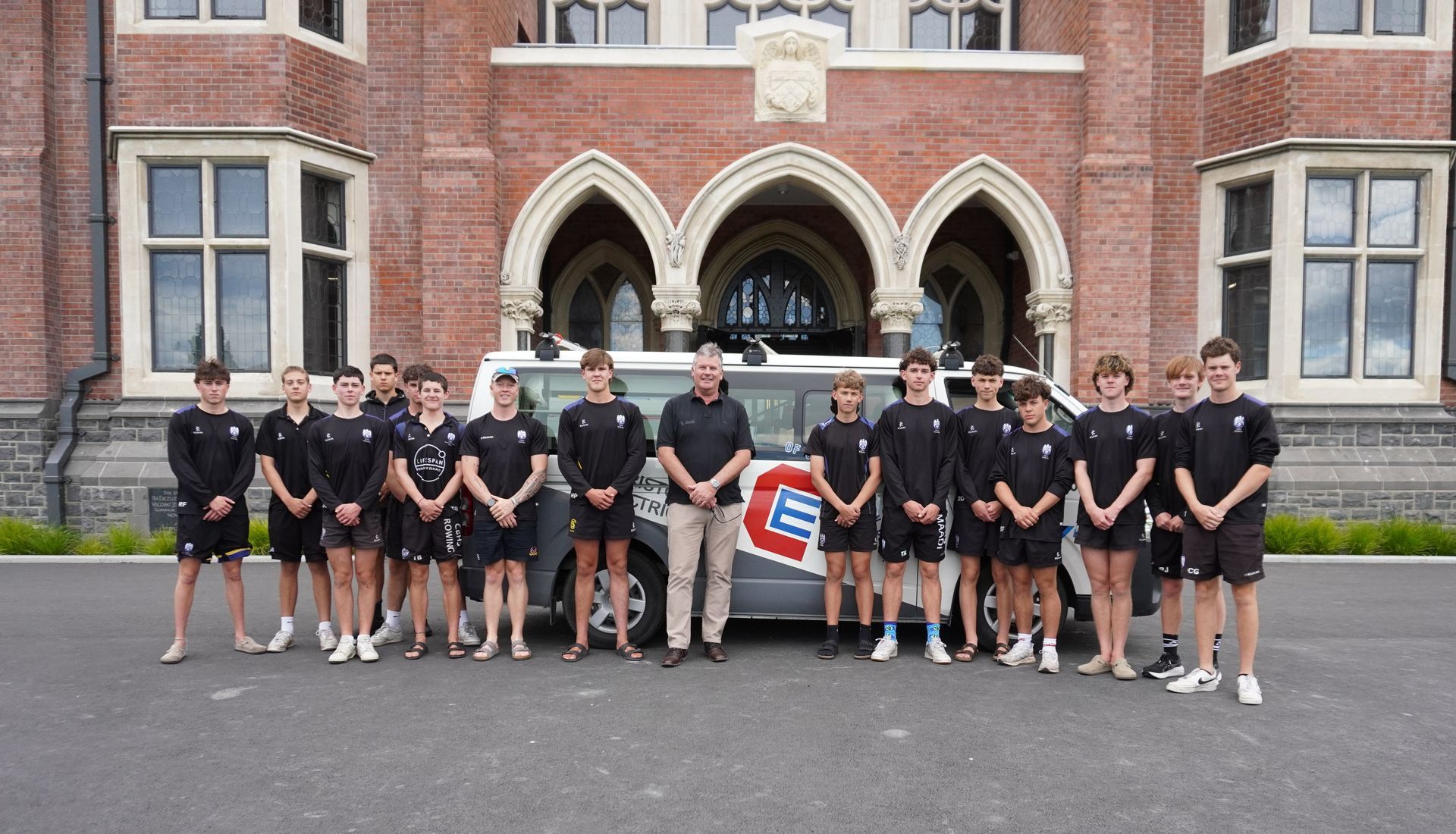 Warren Bentley with Christchurch Electrical van and Christchurch Boys High School Rowing team in front of CBHS.
