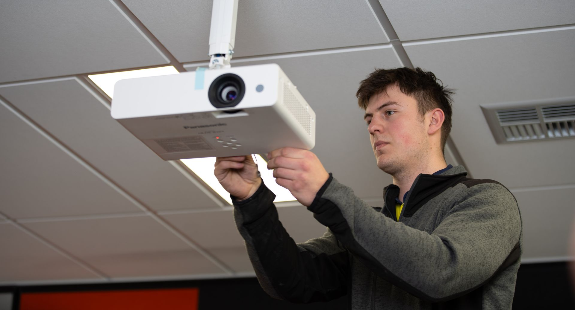 William Bentley of Christchurch Electrical adjusting a projector at BrainTree Wellness Centre. 