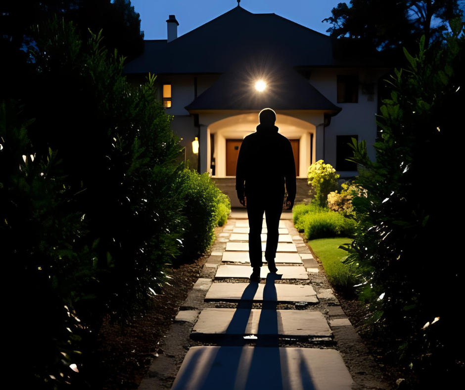 Dark figure of a man walking away from a house with security lighting