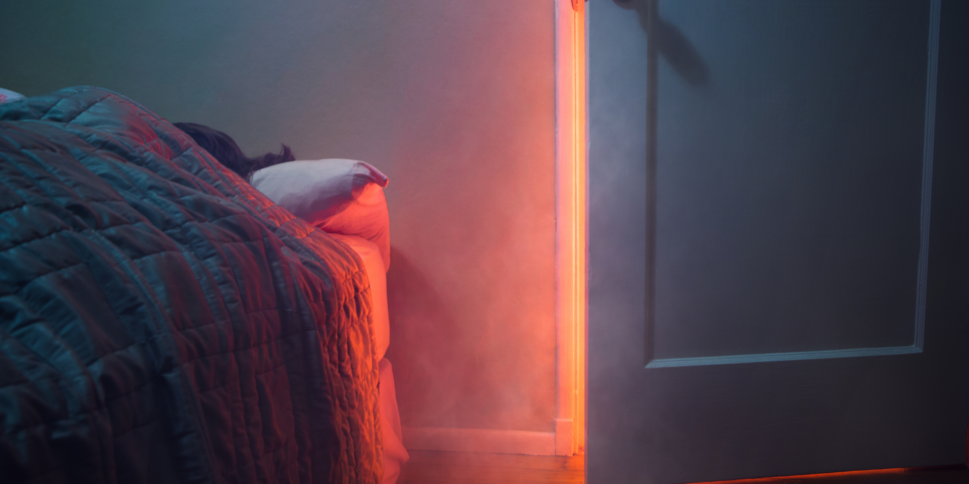 Person in bed, smoke from a fire coming in through an open door.