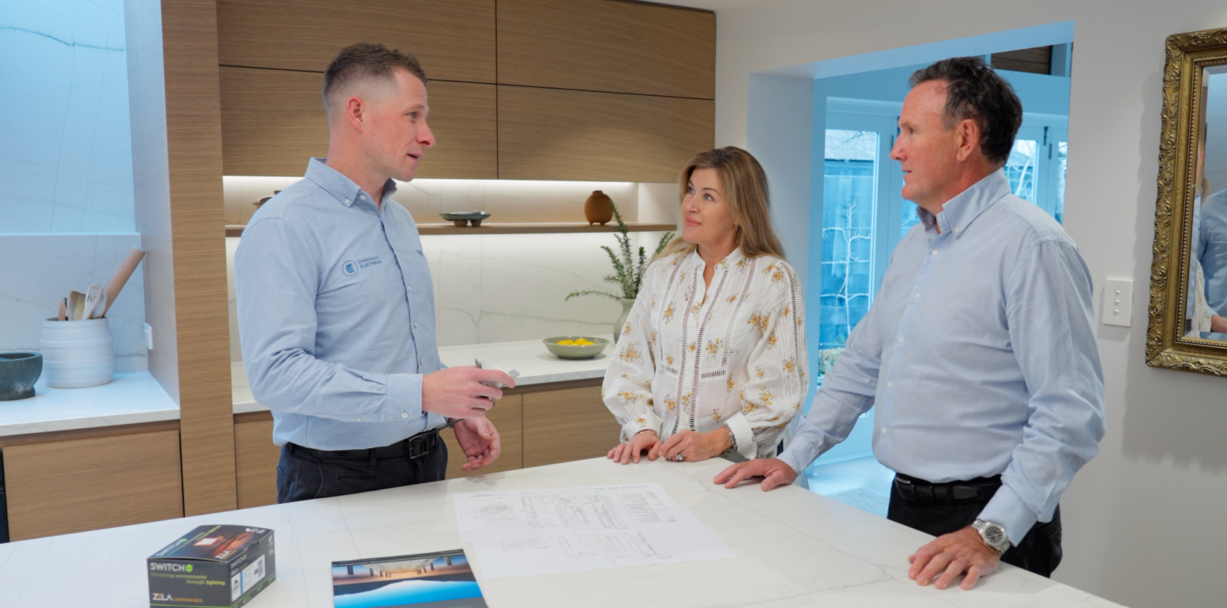 Jared Welsh - Director of Christchurch Electrical and Katie and David Gyde discussing lighting options in their kitchen