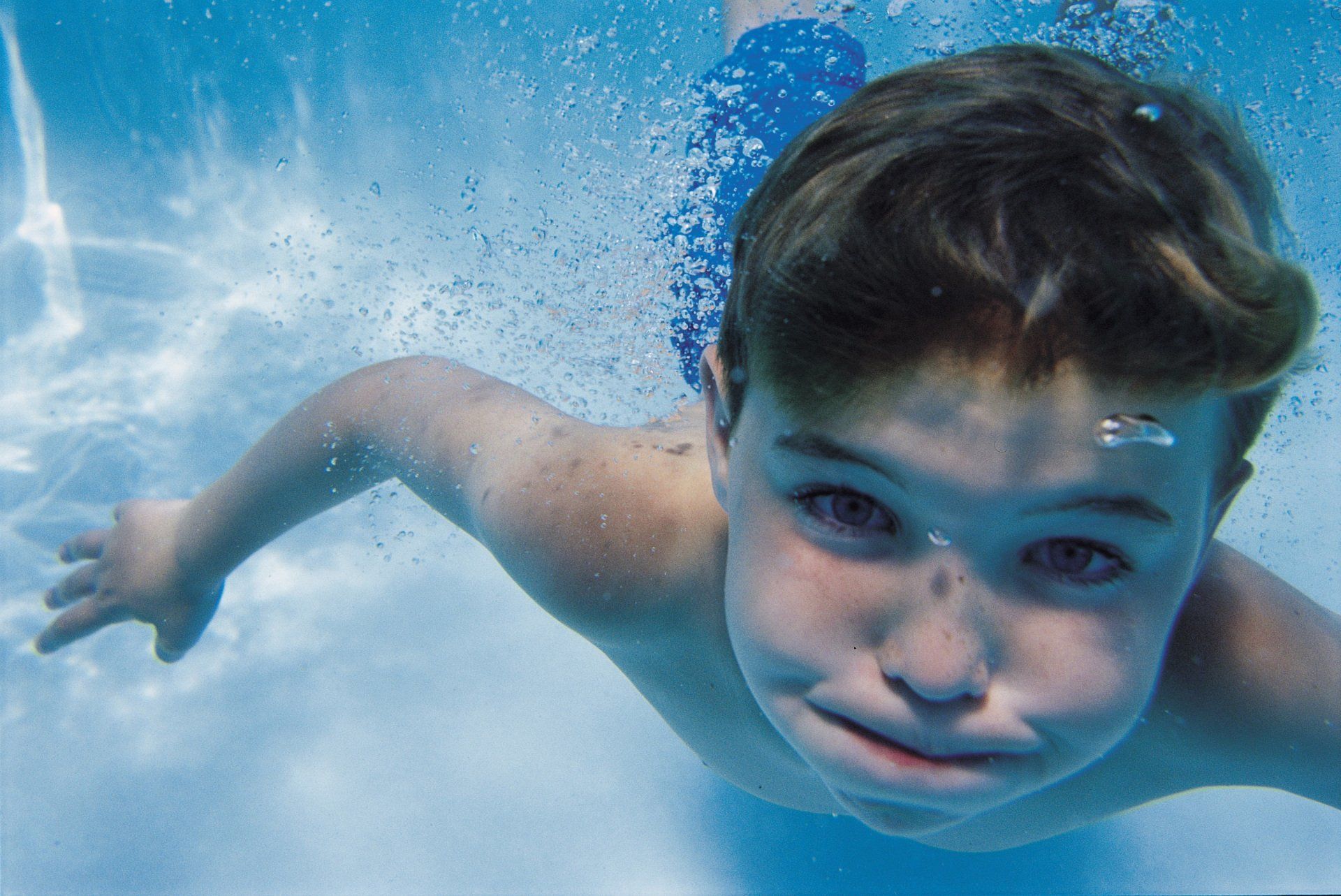 Boy Swimming Under Water In Swimming Pool