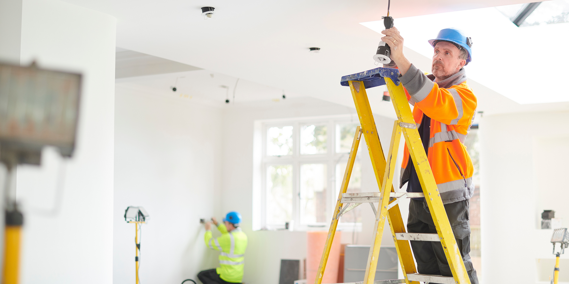 Electrician on ladder fitting a light