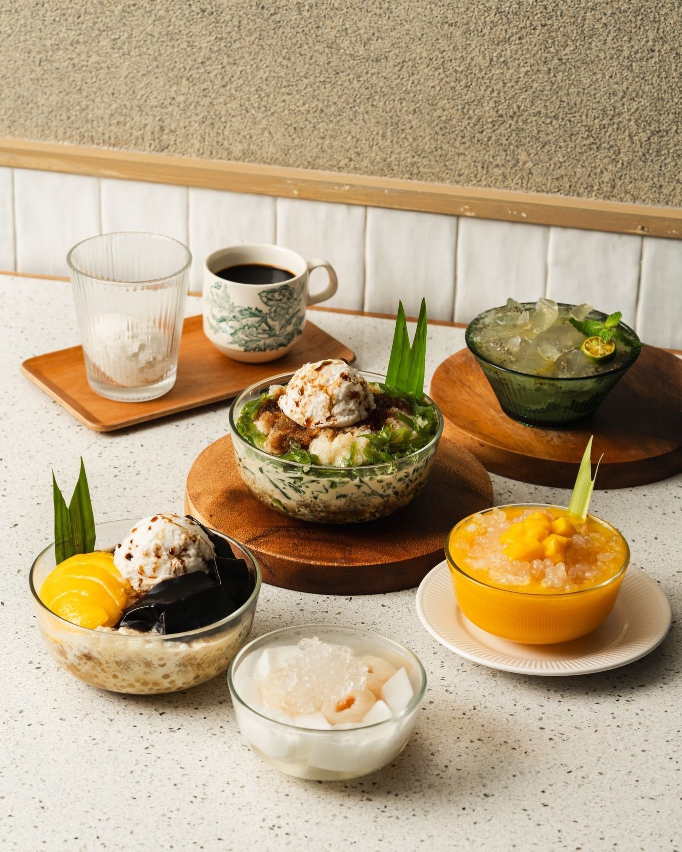 Various colorful desserts and drinks on a counter: shaved ice, ice cream, coffee.