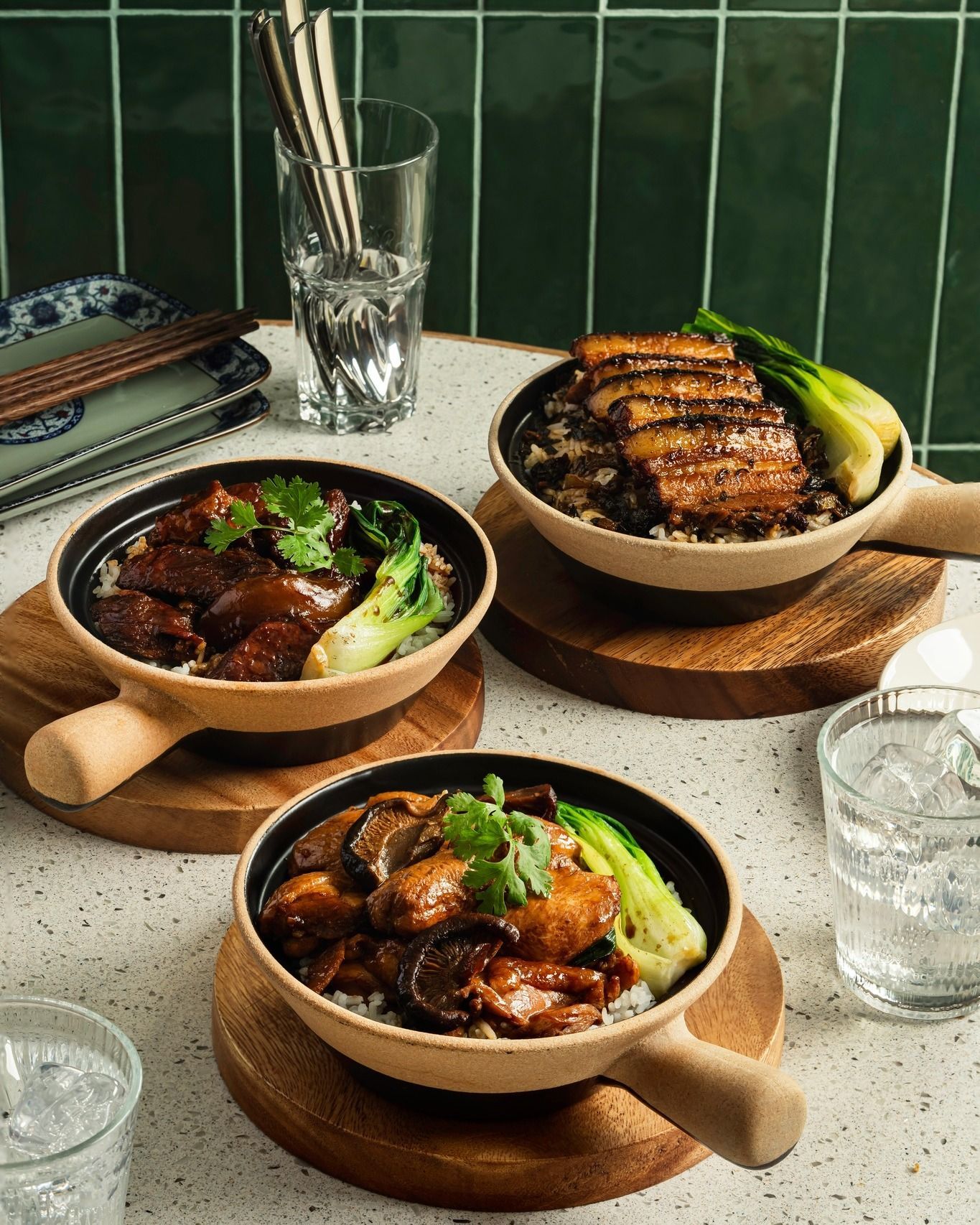 Three bowls of food are sitting on a wooden cutting board on a table.