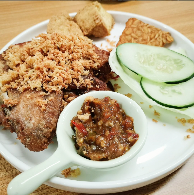 Fried chicken meal with rice, cucumber slices and sauce in a casual dining setting