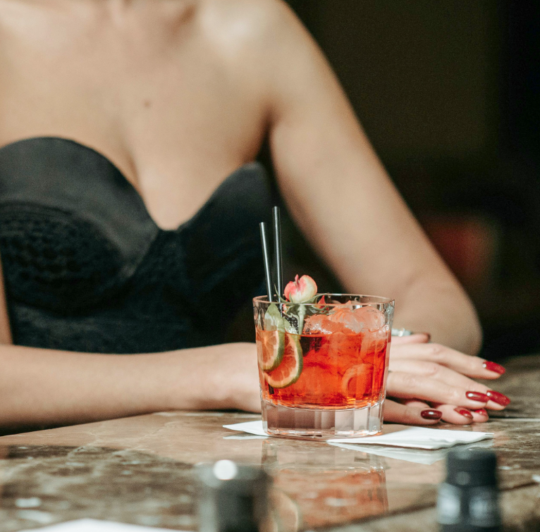 A woman is sitting at a table with a drink in front of her