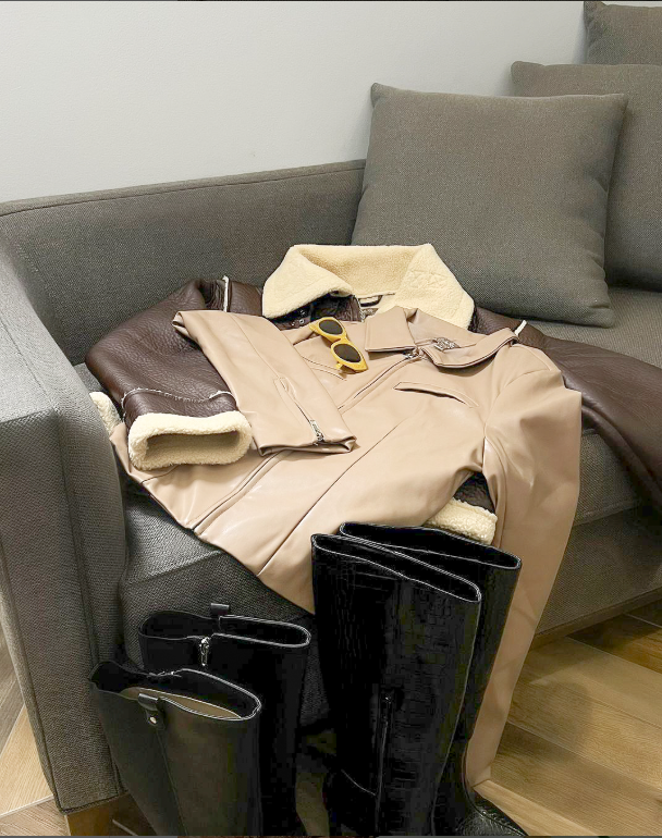 A couch with a jacket and boots on it